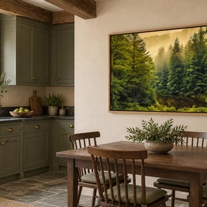 May include: A large rectangular framed wall art piece depicting a dense, misty forest with tall green pine trees and golden light. The artwork is mounted on a light-colored wall above a wooden dining table with chairs in a kitchen.