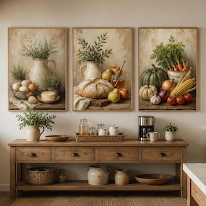 May include: Three framed wall art prints depicting kitchen still lifes. The left shows eggs and a pitcher, the center features bread and honey, and the right displays fresh vegetables including a pumpkin, carrots, corn, and tomatoes.