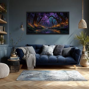 Op de afbeelding: Een ingelijst landschapsschilderij dat een mystieke bossc&egrave;ne met een reflecterend water weergeeft. Het kunstwerk heeft een donker kleurenpalet met paarse, blauwe en oranje tinten. Het schilderij hangt boven een blauwe bank met decoratieve kussens.