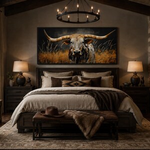 May include: A rustic bedroom with a large bed, dark wood furniture, and a large painting of a longhorn. The room features a bench with a hat and fur throw, two bedside lamps, and a chandelier. The color palette is warm, with browns and tans.
