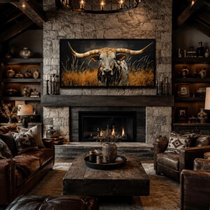 May include: A rustic living room with a stone fireplace and a large painting of a longhorn. The room features leather furniture, wooden beams, and decorative shelves. A coffee table sits in front of the fireplace, and a lamp provides warm lighting.