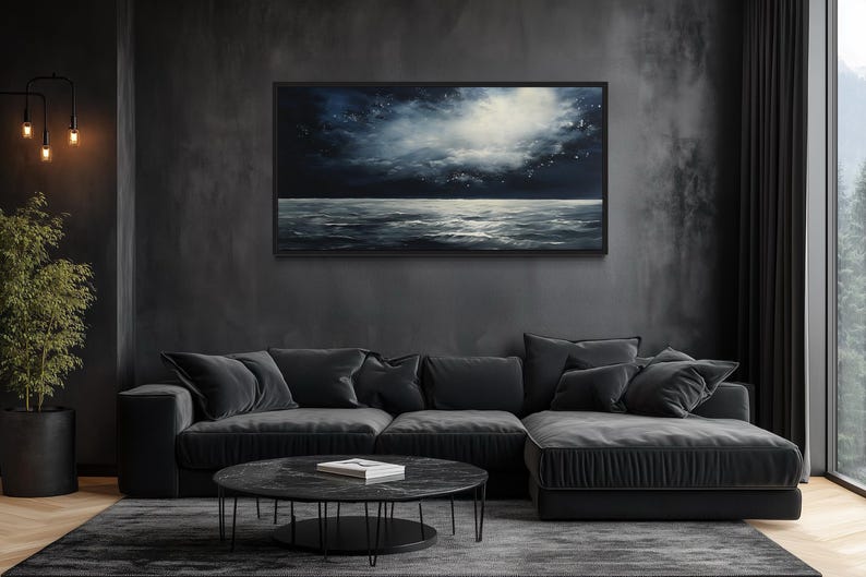 a modern living room with a large black sectional sofa, a round black coffee table, and a large black painting hanging on the wall above the sofa.