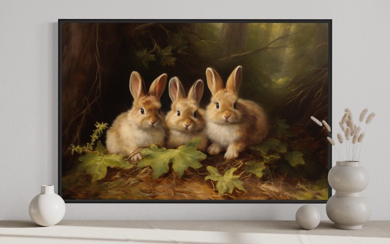 A framed painting of three rabbits sitting on a bed of leaves and branches, surrounded by a forest setting.
