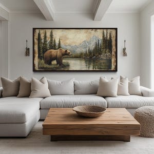 a large painting of a bear in a forest setting, hanging on the wall above a white sectional sofa with beige pillows. The sofa is positioned in front of a wooden coffee table, and there is a large window in the background that provides a view of the outdoors.
