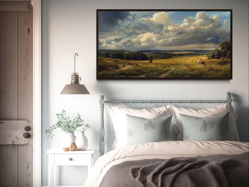 a serene bedroom scene with a large landscape painting hanging on the wall above a bed with white pillows and a gray blanket.