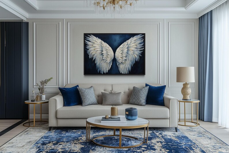 a luxurious living room with a large, striking painting of white wings on the wall. The room is furnished with a white sofa, a round coffee table, and a chandelier overhead. The overall decor has a modern and elegant style, with a blue and white color scheme.