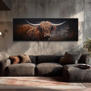 a large painting of a horned animal, possibly a yak or a bull, hanging on a wall above a gray sectional sofa in a modern living room setting.