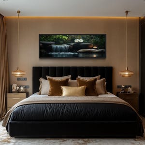 a luxurious bedroom with a large bed, dark headboard, and gold accents. The bed is adorned with a black comforter and gold throw pillows. Above the bed, there is a framed picture of a waterfall and flowers. The room features a large window with beige curtains, and the walls are painted in a light brown color. There are two pendant lights hanging above the bed, and a white dresser is visible on the right side of the room.