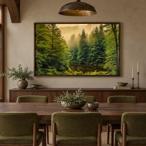 May include: A rectangular framed wall art print depicting a misty forest landscape with dense green pine trees, mounted above a dark wooden sideboard and a matching dining table with six olive green upholstered chairs.