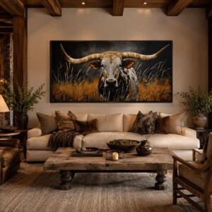 May include: A living room with a large painting of a longhorn bull above a cream-colored sofa. The room features a rustic wooden coffee table, leather armchairs, and a stone fireplace, creating a warm and inviting atmosphere. The decor includes throw pillows and decorative vases.