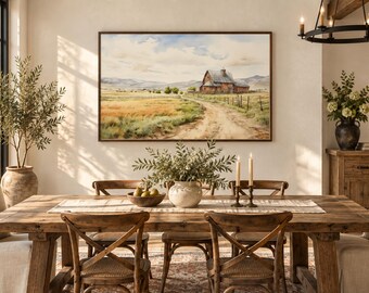 Könnte beinhalten: Ein rechteckiges Landschaftsgemälde mit einer rustikalen roten Scheune auf einem weiten, goldenen Feld unter einem bewölkten Himmel. Das Kunstwerk ist in einen dünnen, dunklen Holzrahmen gefasst und hängt an einer hellen Wand über einem Holztisch.