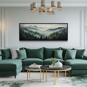 May include: A modern living room featuring a large, emerald green sectional sofa with several throw pillows. A landscape painting of a misty mountain scene hangs above the sofa. Two round coffee tables and a potted plant complete the decor.