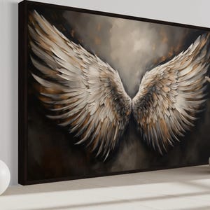 a large painting of a pair of angelic wings, with a dark background and a lighter color scheme. The painting is displayed on a wall, and there are two white vases and a small white ball placed next to it.