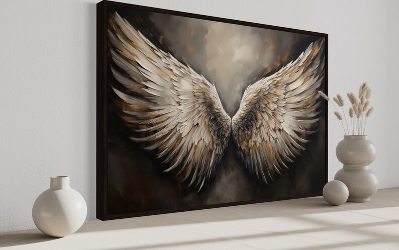 a large painting of a pair of angelic wings, with a dark background and a lighter color scheme. The painting is displayed on a wall, and there are two white vases and a small white ball placed next to it.
