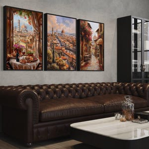 a modern living room with a large brown leather sofa, a white coffee table, and three framed paintings hanging on the wall above the sofa.