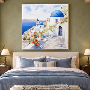 May include: A square wall art print featuring a painting of a Mediterranean coastal village with white buildings, iconic blue domes, and vibrant orange flowers cascading over a stone wall, all set against a deep blue sea and sky.