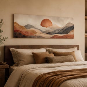 May include: A bedroom scene featuring a large landscape canvas with a sunset over layered mountains in shades of orange, brown, and gray. The bed has beige bedding with brown pillows and a matching throw. A wooden nightstand and shelves complete the warm, inviting space.