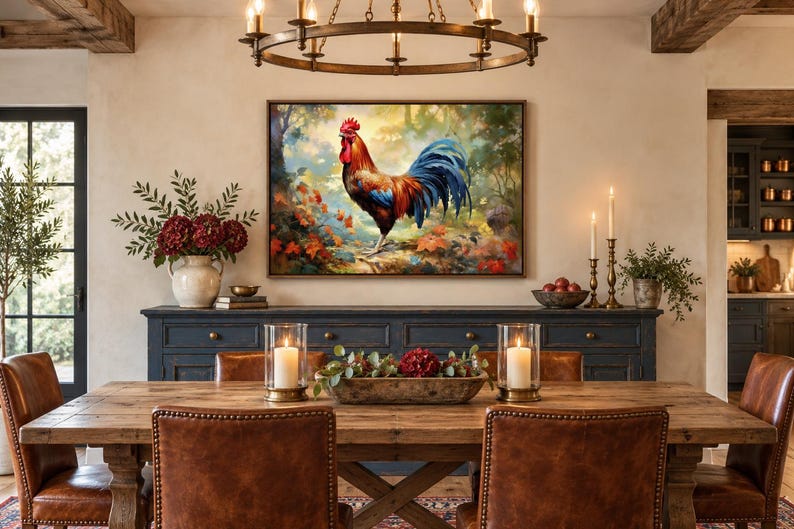 May include: A rectangular wall art print featuring a vibrant rooster with red, orange, and blue plumage standing in a forest setting with autumn leaves. The artwork is framed in a dark wood border and displayed above a long, dark blue wooden sideboard.
