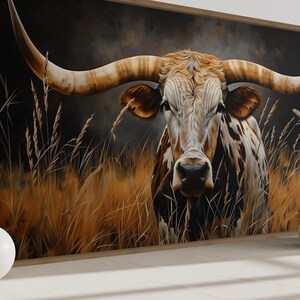 a large painting of a bull with long horns, set against a backdrop of tall grass and a dark background. The bull is the central focus of the painting, with its horns prominently displayed. The painting is framed and hung on a wall, creating a striking visual focal point in the room.
