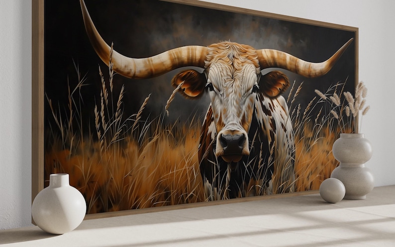 a large painting of a bull with long horns, set against a backdrop of tall grass and a dark background. The bull is the central focus of the painting, with its horns prominently displayed. The painting is framed and hung on a wall, creating a striking visual focal point in the room.