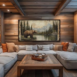 a cozy living room with a large painting of a bear in a forest scene hanging on the wall. The room has a rustic, cabin-like atmosphere with wooden walls and ceiling, and a comfortable couch and coffee table arranged around the space.