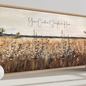 May include: A framed landscape art print depicting a field of wildflowers in shades of brown, orange, and white under a cloudy sky. The text "Your Custom Scripture Here" is written across the top. Decorative vases and a sphere are in the foreground.