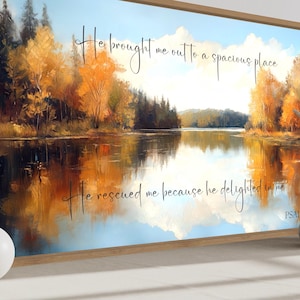 Pode incluir: Pintura de paisagem emoldurada que retrata uma serena cena lacustre com folhagem de outono em tons de ouro e laranja. A obra de arte inclui o texto "Ele me tirou para um lugar espaçoso" e "Ele me resgatou, porque se agradou de mim" do Salmo 18:19.