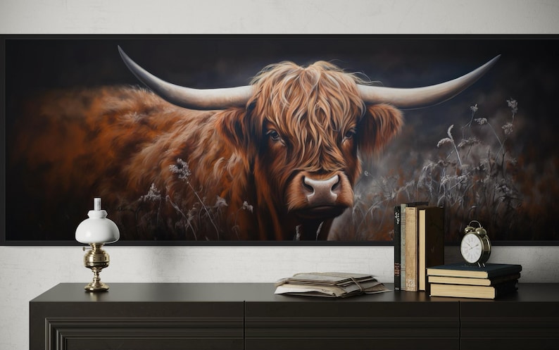 a large painting of a horned animal, likely a yak or a bull, with a dark background and a lighter background. The painting is displayed on a wall, and there is a lamp and some books on a table in front of it.