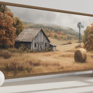 May include: Framed landscape art featuring a rustic barn, windmill, and hay bale in a field. The artwork has a warm color palette of browns, yellows, and greens, evoking a rural autumn scene. The frame is a warm brown.