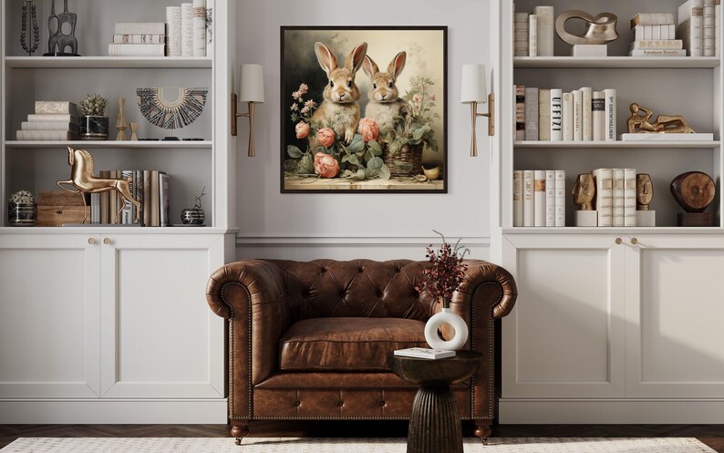 a cozy living room with a brown leather armchair, a wooden side table, and a framed painting of two rabbits sitting on a shelf. The room is decorated with various books, vases, and other knick-knacks, creating a warm and inviting atmosphere.