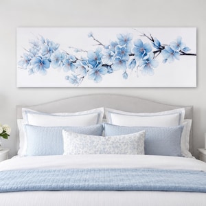 Op de afbeelding: Een rechthoekig canvas wandkunstwerk met een horizontale tak met lichtblauwe en witte kersenbloesems. De bloemen zijn geschilderd in verschillende tinten blauw, variërend van licht hemelsblauw tot dieper azuurblauw, op een effen witte achtergrond.