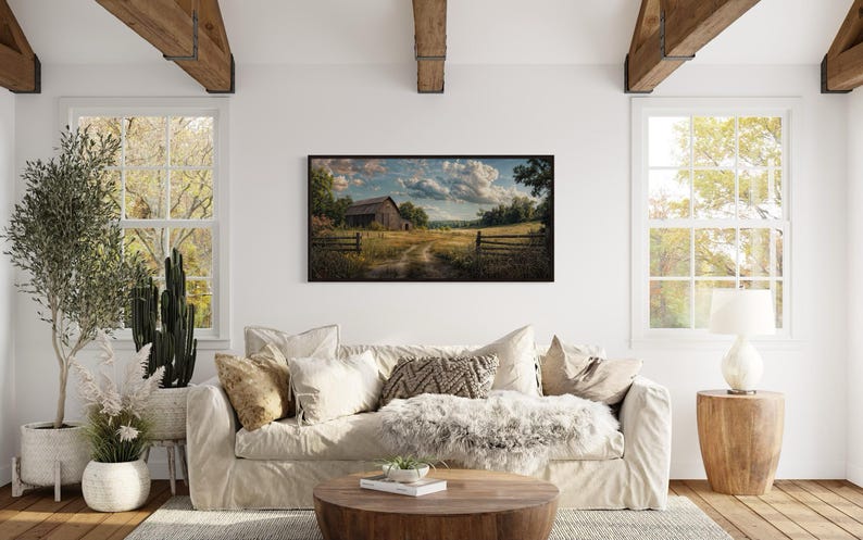 a cozy living room with a large window overlooking a rural landscape, featuring a barn and a field. The room is decorated with a white sofa, a wooden coffee table, and various potted plants, creating a warm and inviting atmosphere.
