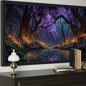 Op de afbeelding: Een ingelijste kunstdruk die een fantasiebossc&egrave;ne met een rivier afbeeldt. Het kunstwerk heeft een donker kleurenpalet met paarse, blauwe en oranje tinten. Een kleine lamp, boeken en een klok staan op een donkerbruin dressoir onder het kunstwerk.