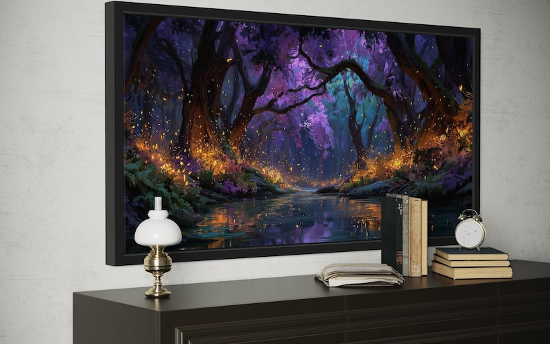 Op de afbeelding: Een ingelijste kunstdruk die een fantasiebossc&egrave;ne met een rivier afbeeldt. Het kunstwerk heeft een donker kleurenpalet met paarse, blauwe en oranje tinten. Een kleine lamp, boeken en een klok staan op een donkerbruin dressoir onder het kunstwerk.