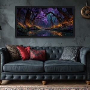 Op de afbeelding: Een ingelijst landschapsschilderij toont een mystieke bossc&egrave;ne met een rivier. Het kunstwerk heeft een donker kleurenpalet met paarse, blauwe en oranje tinten. Het schilderij hangt boven een donkerblauwe gecapitonneerde bank met decoratieve kussens.