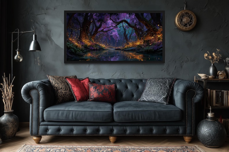 Op de afbeelding: Een ingelijst landschapsschilderij toont een mystieke bossc&egrave;ne met een rivier. Het kunstwerk heeft een donker kleurenpalet met paarse, blauwe en oranje tinten. Het schilderij hangt boven een donkerblauwe gecapitonneerde bank met decoratieve kussens.