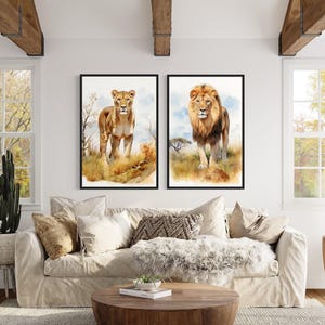 a living room with a large window, a white sofa, and two framed paintings of lions on the wall.