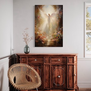 a large painting of an angel with wings, hanging on a wall above a wooden cabinet or dresser. The painting is surrounded by a floral arrangement, and there is a woven chair in the foreground.