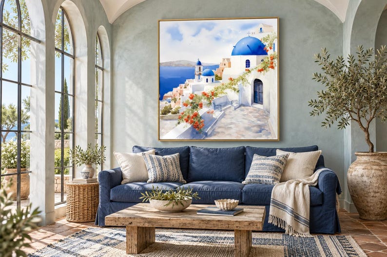 May include: A square wall art print featuring a Mediterranean coastal scene with white buildings, bright blue domes, and vibrant orange flowers overlooking a deep blue sea, framed in a thin gold border and displayed on a wall.