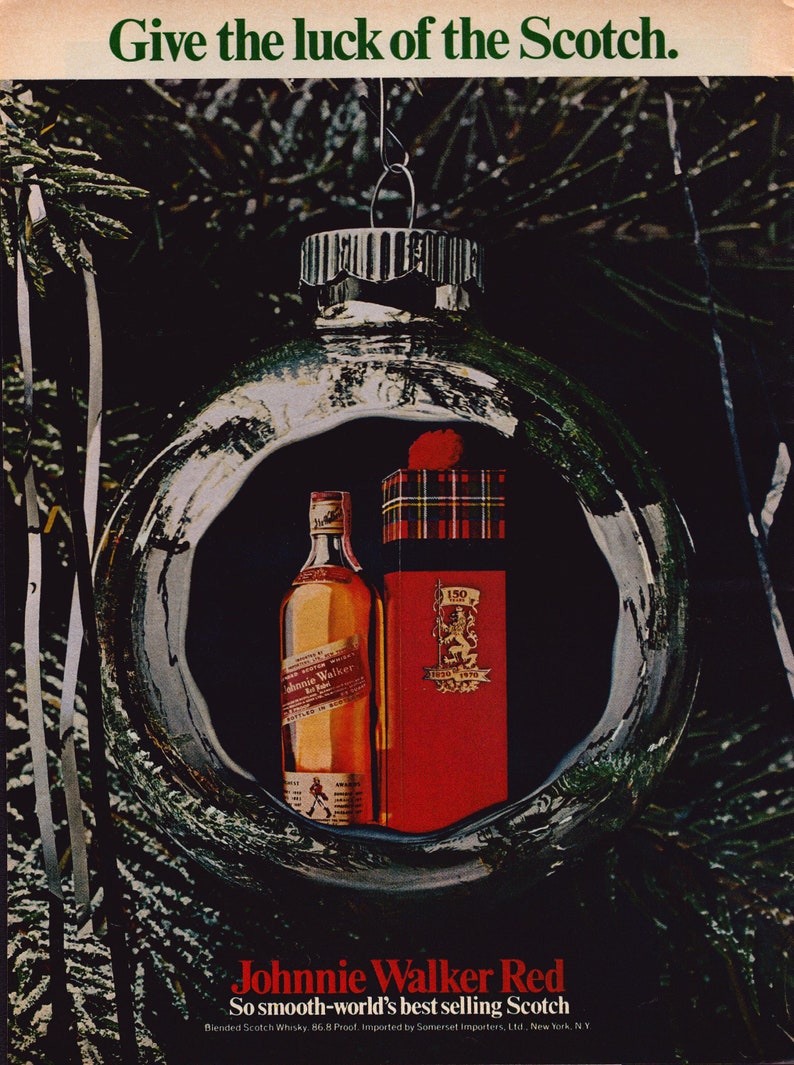 May include: A vintage advertisement for Johnnie Walker Red Label whisky, featuring a bottle and a red gift box inside a Christmas bauble. The text reads "Give the luck of the Scotch." and "Johnnie Walker Red".