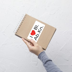 May include: A brown notebook with a white sticker that says "I ♥ BI. Ab.kn.". The sticker has a red heart with a white outline.