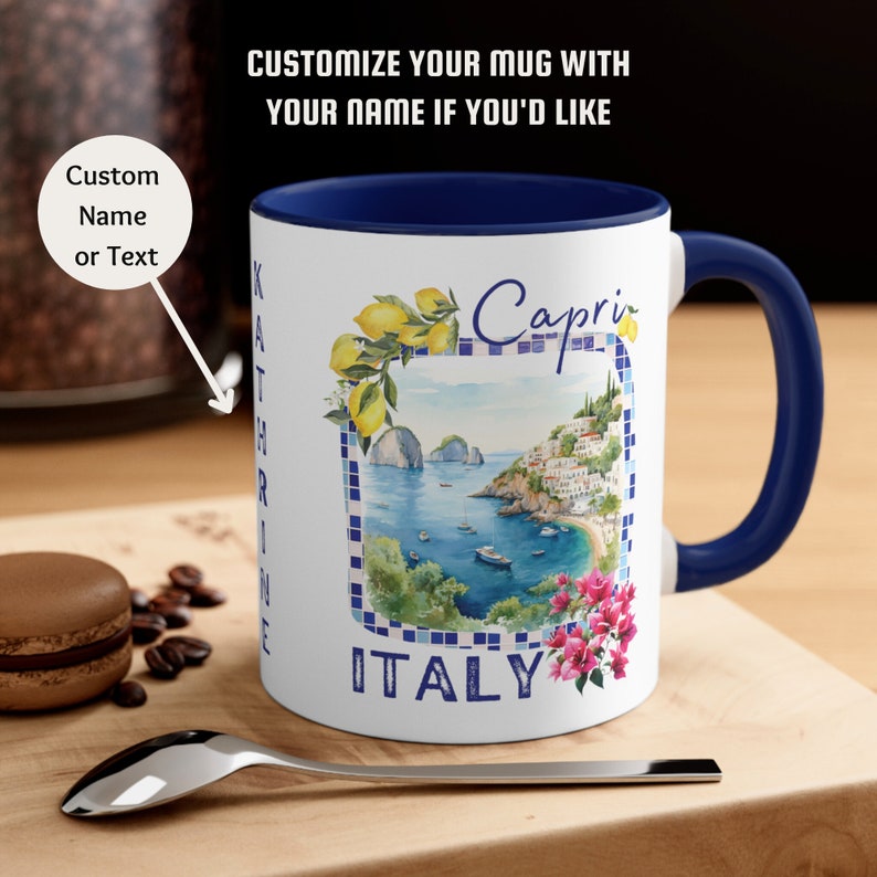 May include: White ceramic mug with a blue rim and handle. The mug features a watercolor illustration of a coastal town with a lemon tree and the text "Capri ITALY".