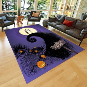 Puede incluir: Alfombra de área púrpura y negra con un letrero de Halloween Town, una luna y la silueta de Jack Skellington. La alfombra presenta una ilustración en blanco y negro de un camino sinuoso con calabazas a lo largo del camino.