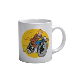 Puede incluir: Taza de cer&aacute;mica blanca con una ilustraci&oacute;n de dibujos animados de un hombre montando una motocicleta azul sobre un fondo amarillo. El hombre lleva un traje marr&oacute;n y una corbata azul. La taza tiene un asa curva.