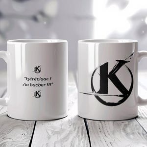 Peut inclure: Deux tasses en céramique blanche avec des motifs noirs. Une tasse a une lettre K noire dans un cercle avec un design de coup de pinceau. L'autre tasse a le texte "Hérétique! Ça bacher!!!" avec un symbole K noir au-dessus et en dessous du texte.