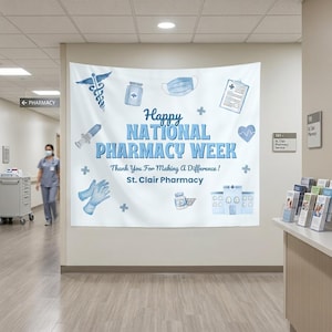 May include: A white wall tapestry featuring blue medical illustrations including a caduceus, syringe, face mask, clipboard, heart, gloves, pill bottle, and building. Text reads: Happy NATIONAL PHARMACY WEEK Thank You For Making A Difference! St. Clair Pharmacy.