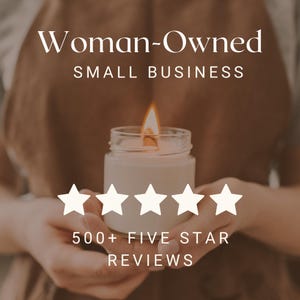 May include: A woman's hands hold a lit candle in a glass jar. The candle is surrounded by five white stars, and the text "Woman-Owned Small Business" and "500+ Five Star Reviews" are visible.