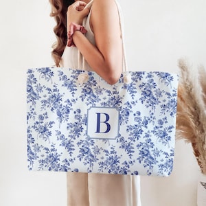 May include: A white tote bag with a blue and white floral pattern and the letter "B" in a blue square in the center.