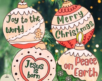 May include: Four Christmas ornaments with festive designs and messages. One ornament says "Joy to the World" with a gingerbread man. Another says "Merry Christmas." The third says "Jesus is born" and the fourth says "Peace on Earth."