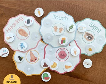 Peut inclure: Jeu de tri éducatif avec le texte "5 Senses Sorting Activity". L'ensemble comprend cinq cartes en forme de fleur étiquetées "Hearing", "Touch", "Sight", "Smell" et "Taste", chacune avec des cartes d'images correspondantes. Un cercle jaune avec le texte "Instant Download" est en bas à gauche.